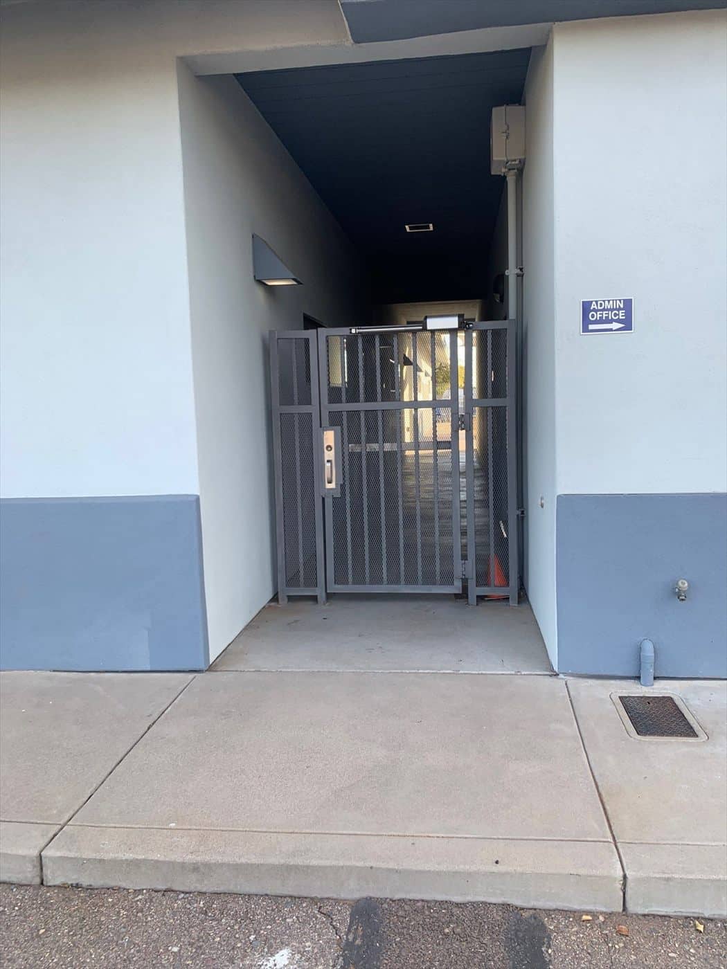 Repainted gray security gate at a two-tone building entrance near the office sign.