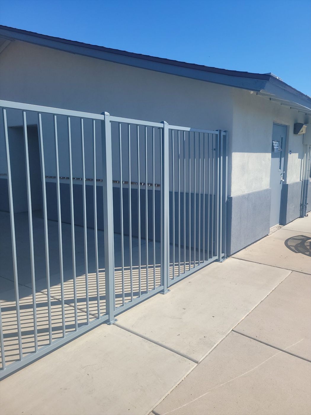 Blue-gray painted metal fence running against the exterior wall of the school building.