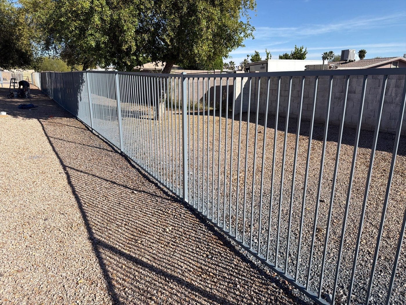 Bare galvanized perimeter fence over gravel prior to painting.