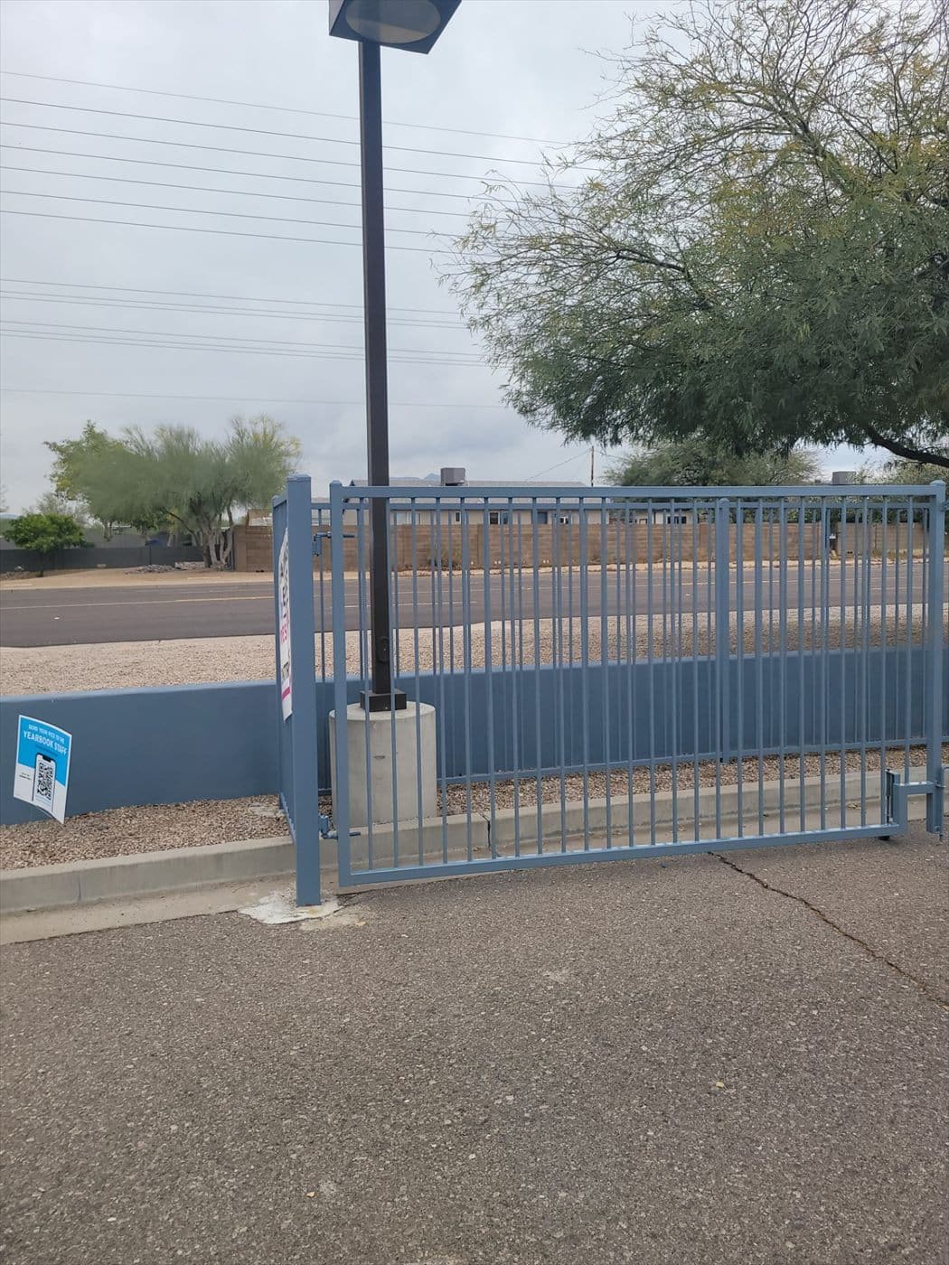 Blue motorized sliding entry gate with operator at the campus street entrance.