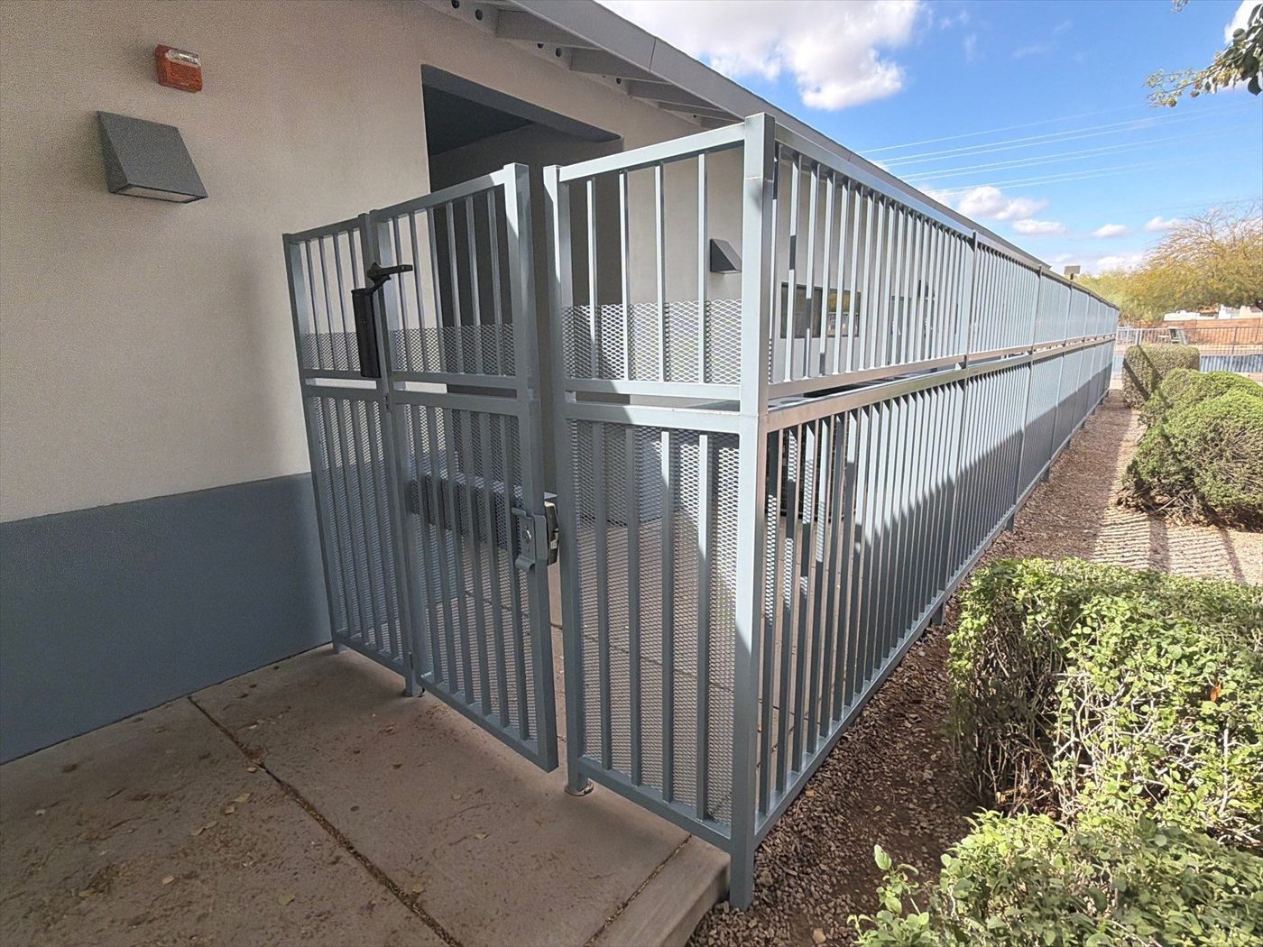 Freshly painted gray metal fence and gate running along the side of the school building.
