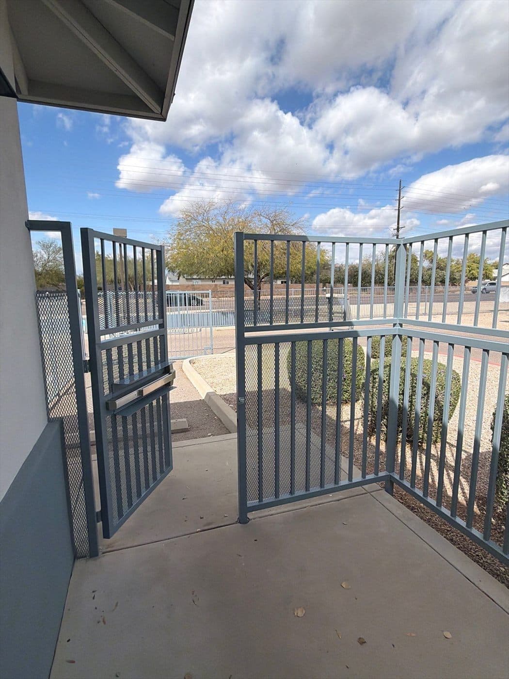 Blue-gray gate and railing enclosing a patio overlooking the campus play area.