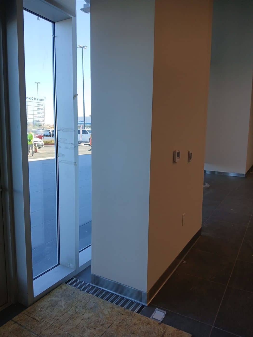 Tan entry vestibule wall by a glass door looking out to the dealership parking lot.