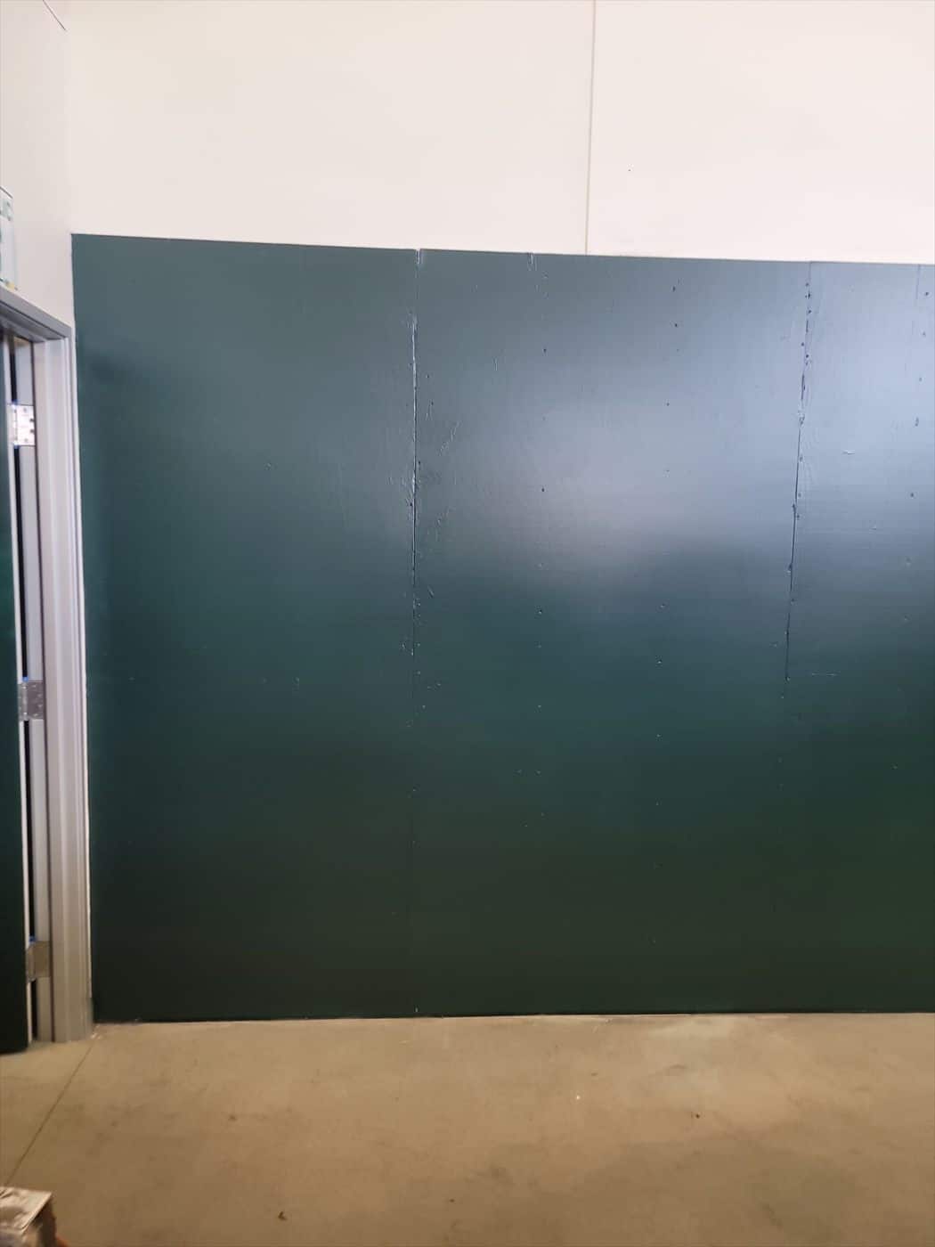Freshly painted dark green paneled wall in a warehouse bay.