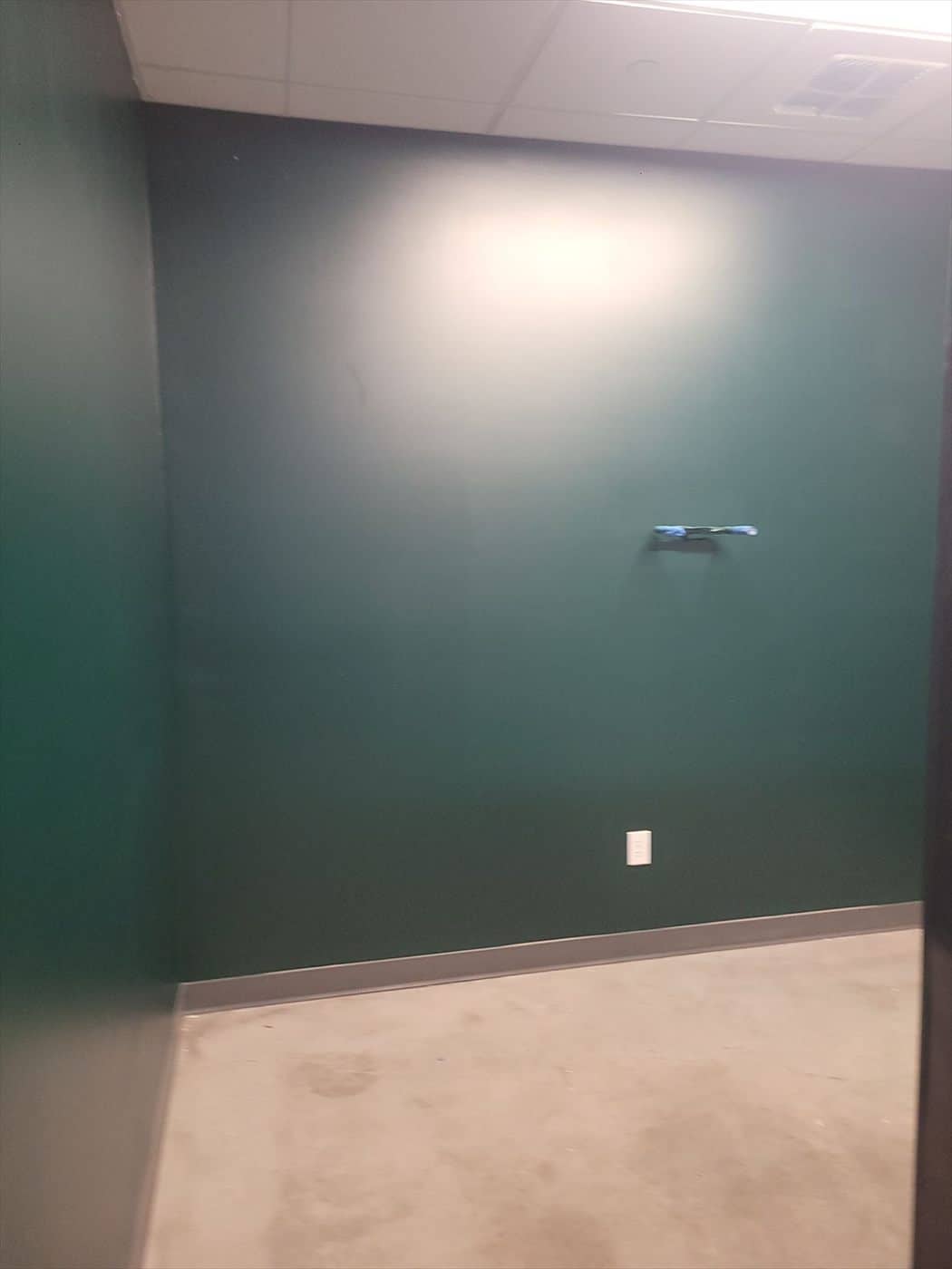 Room with dark green painted walls and exposed concrete floor.