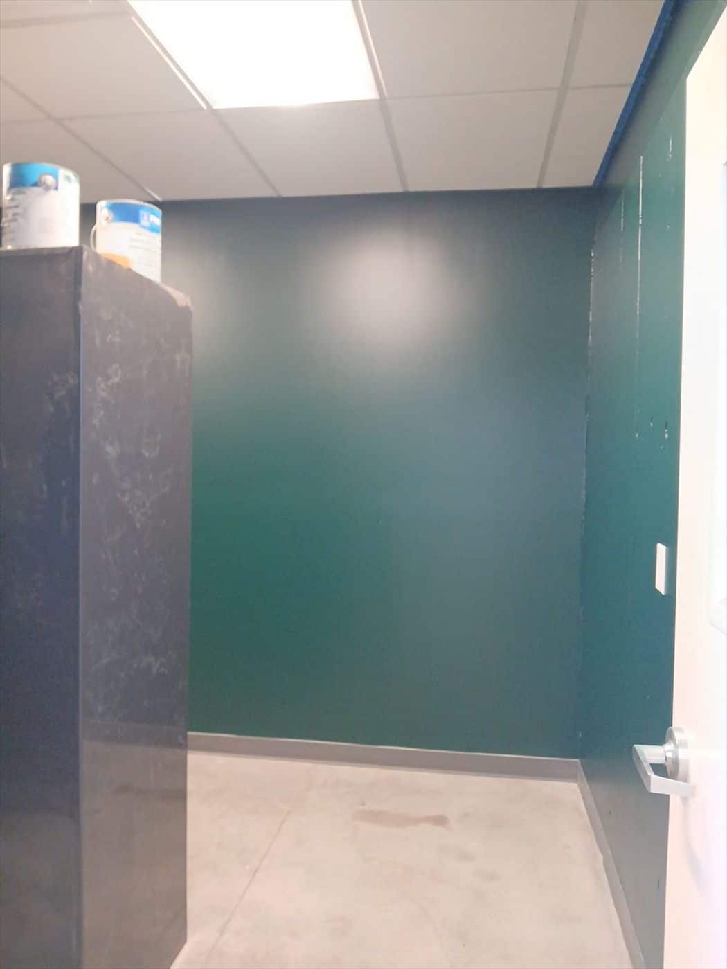 Interior room with newly painted dark green wall and ceiling tile.