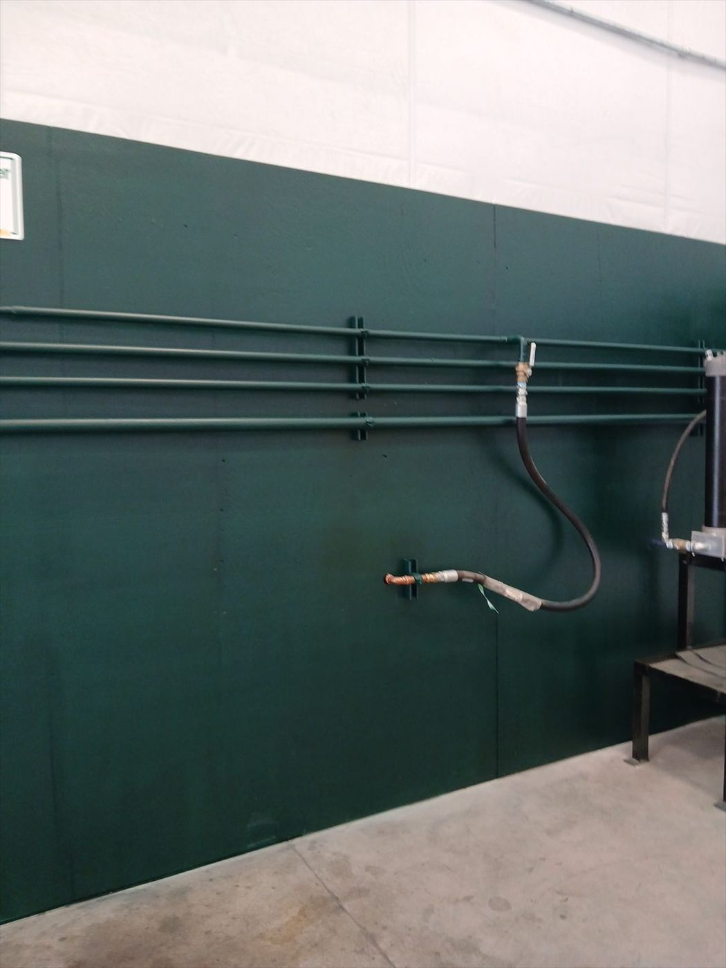 Painted green shop wall with mounted air lines and hose reel.