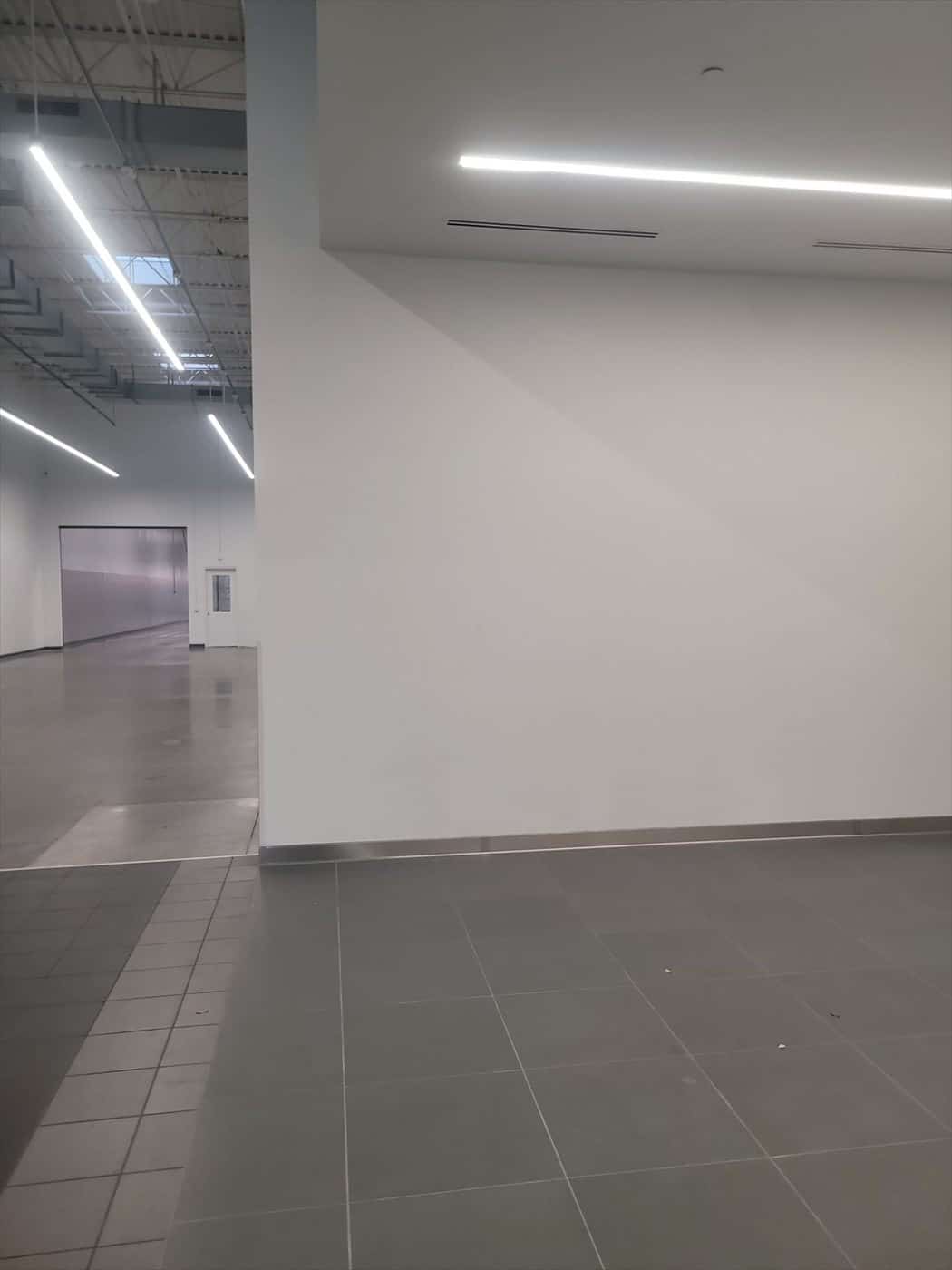 Finished open interior area with white walls, tile flooring and mixed ceilings.