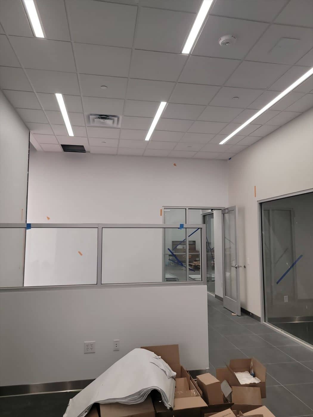 Finished office room with drop ceiling, whiteboards and glass partition wall.