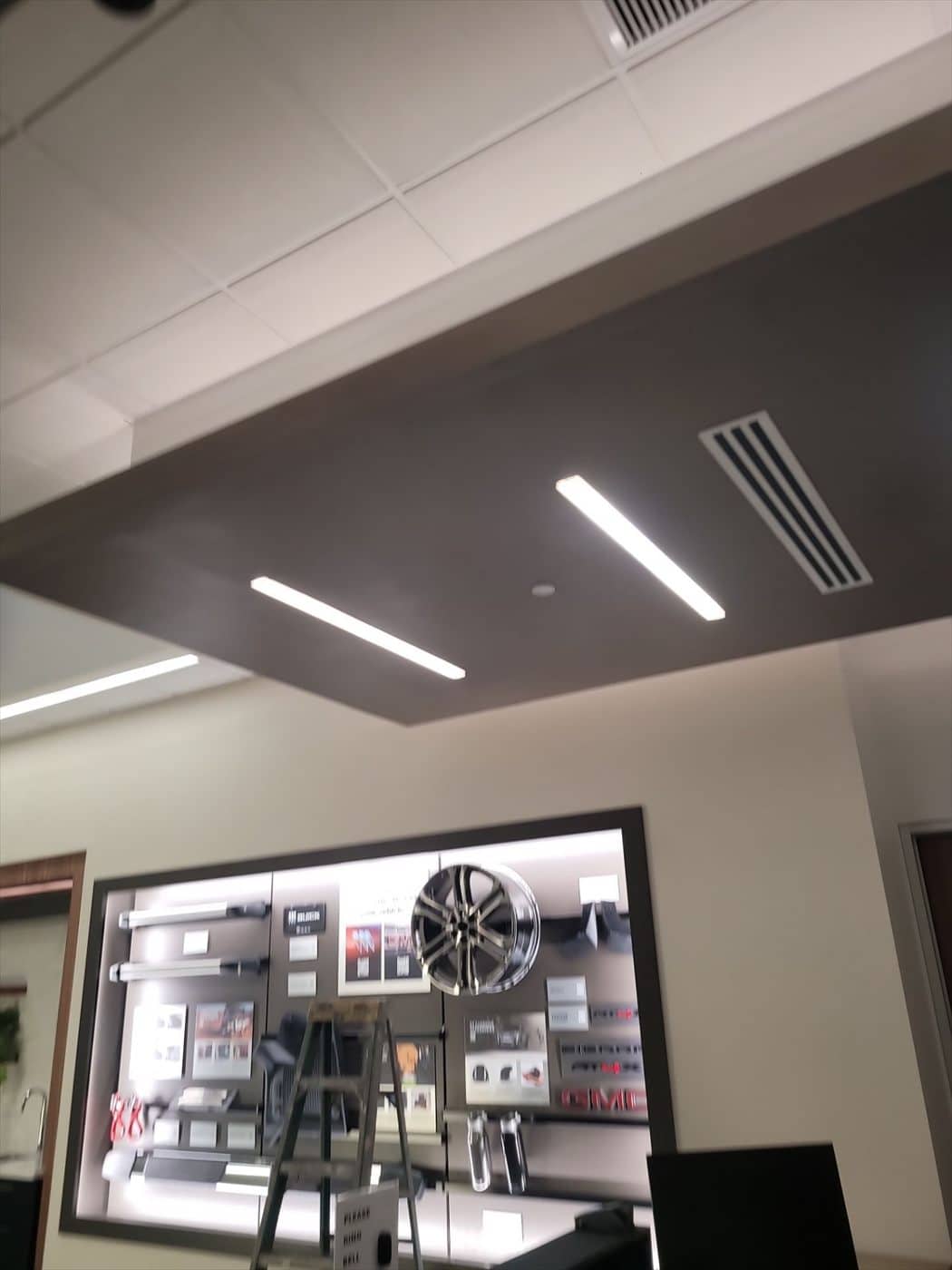 Finished dark gray soffit ceiling with lighting above a GMC wheel and parts display.