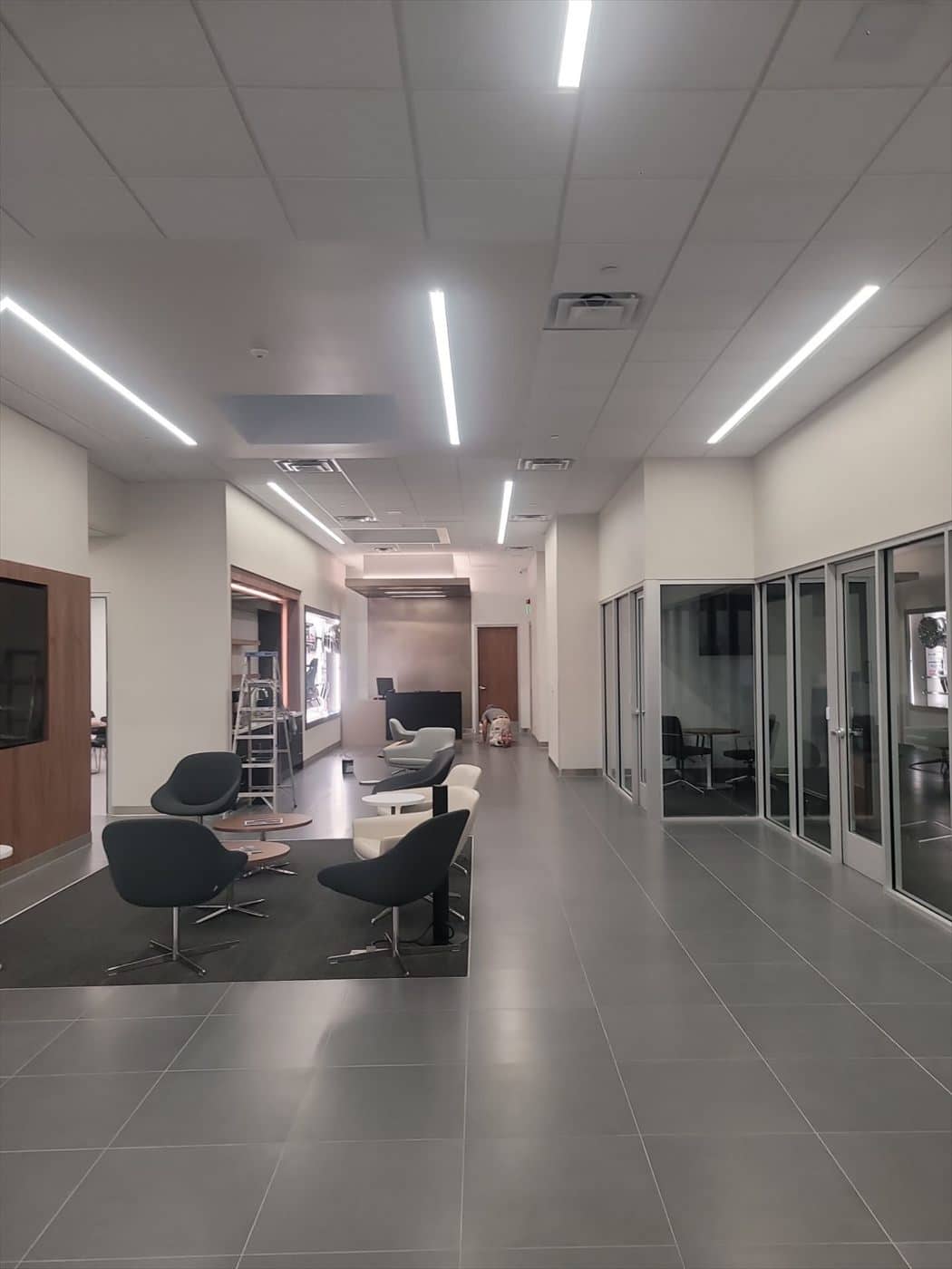Finished showroom lounge with seating, tile floor and glass-walled offices.