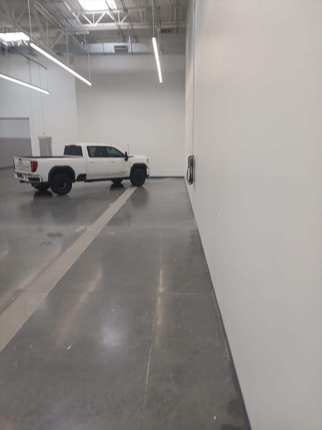 White GMC pickup parked in a finished showroom with polished floors and white walls.