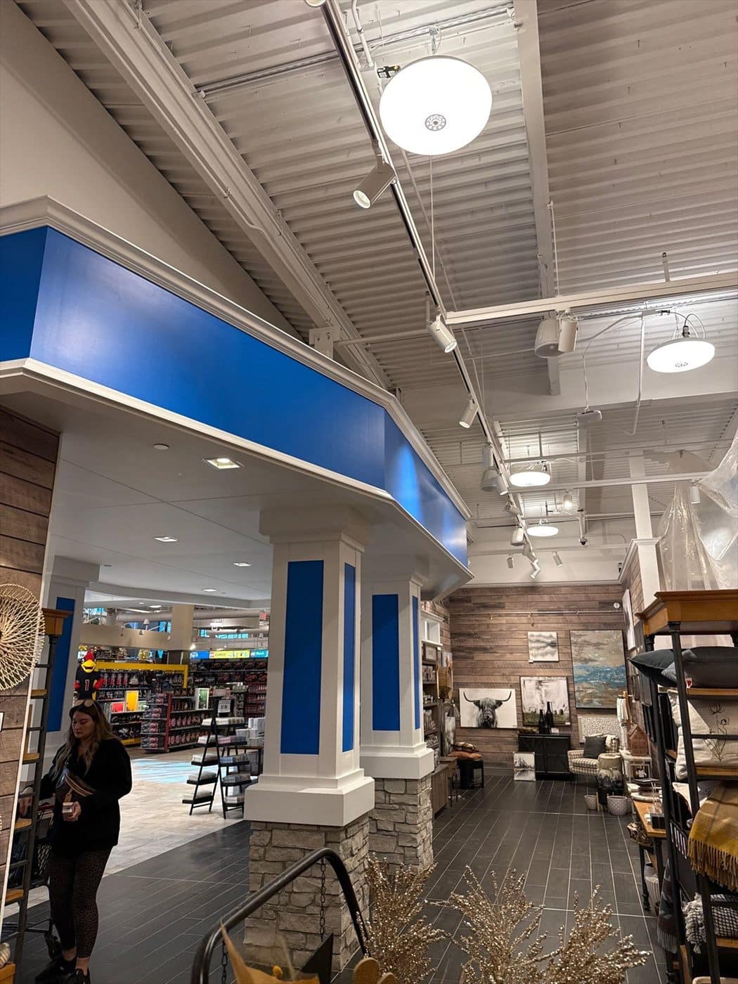 Finished blue soffit and white columns marking a department entrance on the sales floor.