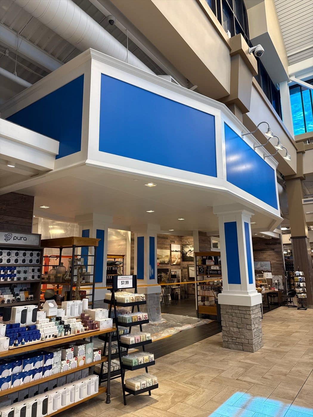 Finished department entry soffit and columns in blue and white above product shelving.