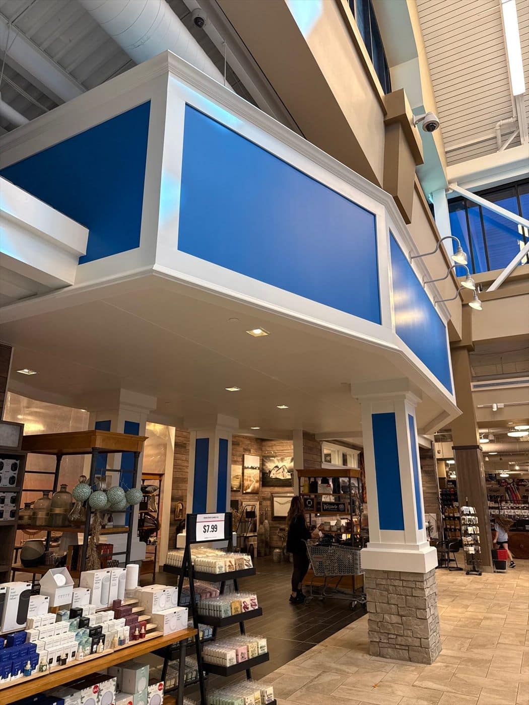 Completed blue-and-white department entry soffit and columns above retail product displays.