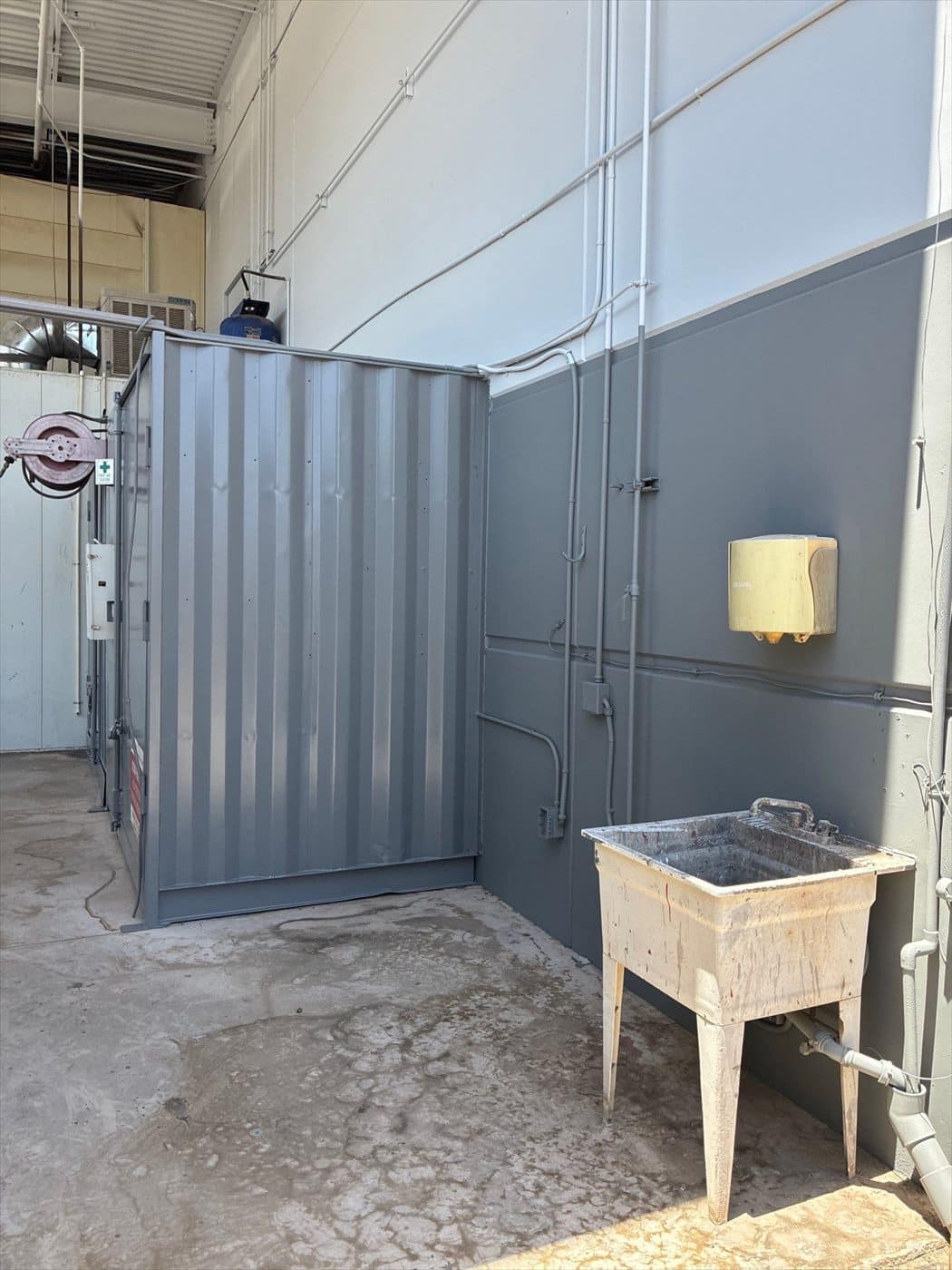 Interior partition wall and container enclosure painted gray beside a utility sink.