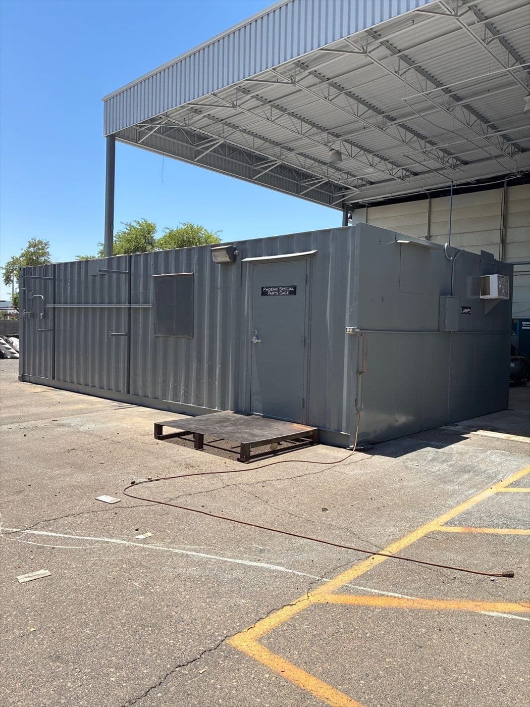 Large storage container enclosure painted gray under an exterior metal canopy.