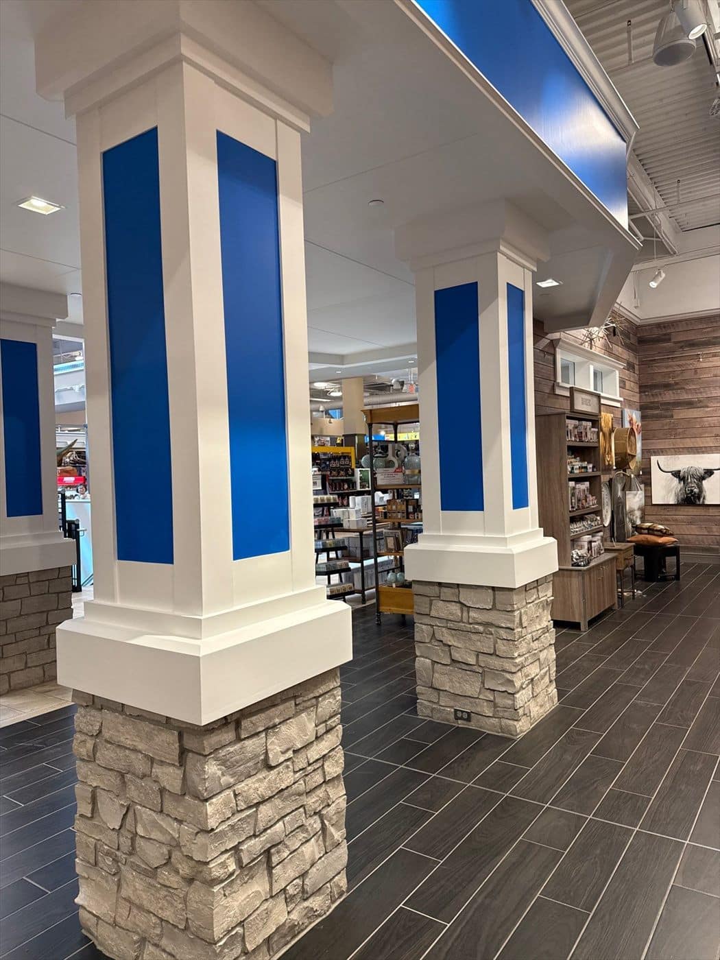 Row of freshly painted white columns with blue accents on stacked-stone bases in the retail interior.