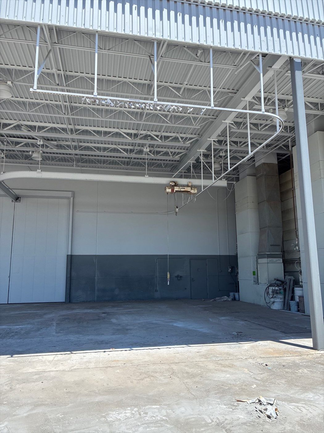 Open warehouse interior bay with exposed steel trusses and freshly painted two-tone walls.