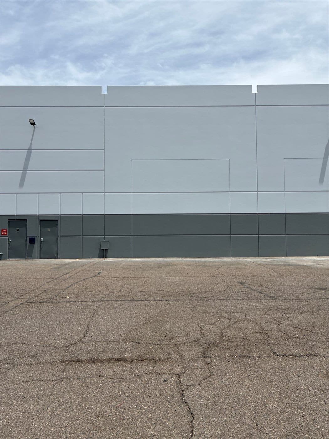 Large tilt-up warehouse wall repainted in a light-gray over dark-gray two-tone scheme.