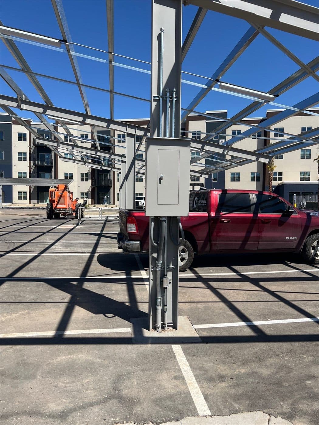 A finished gray-painted electrical box on a carport column with a red truck parked beneath the canopy.