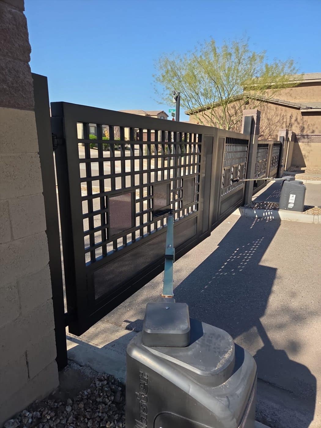Dark decorative metal sliding gate with automated gate operator.