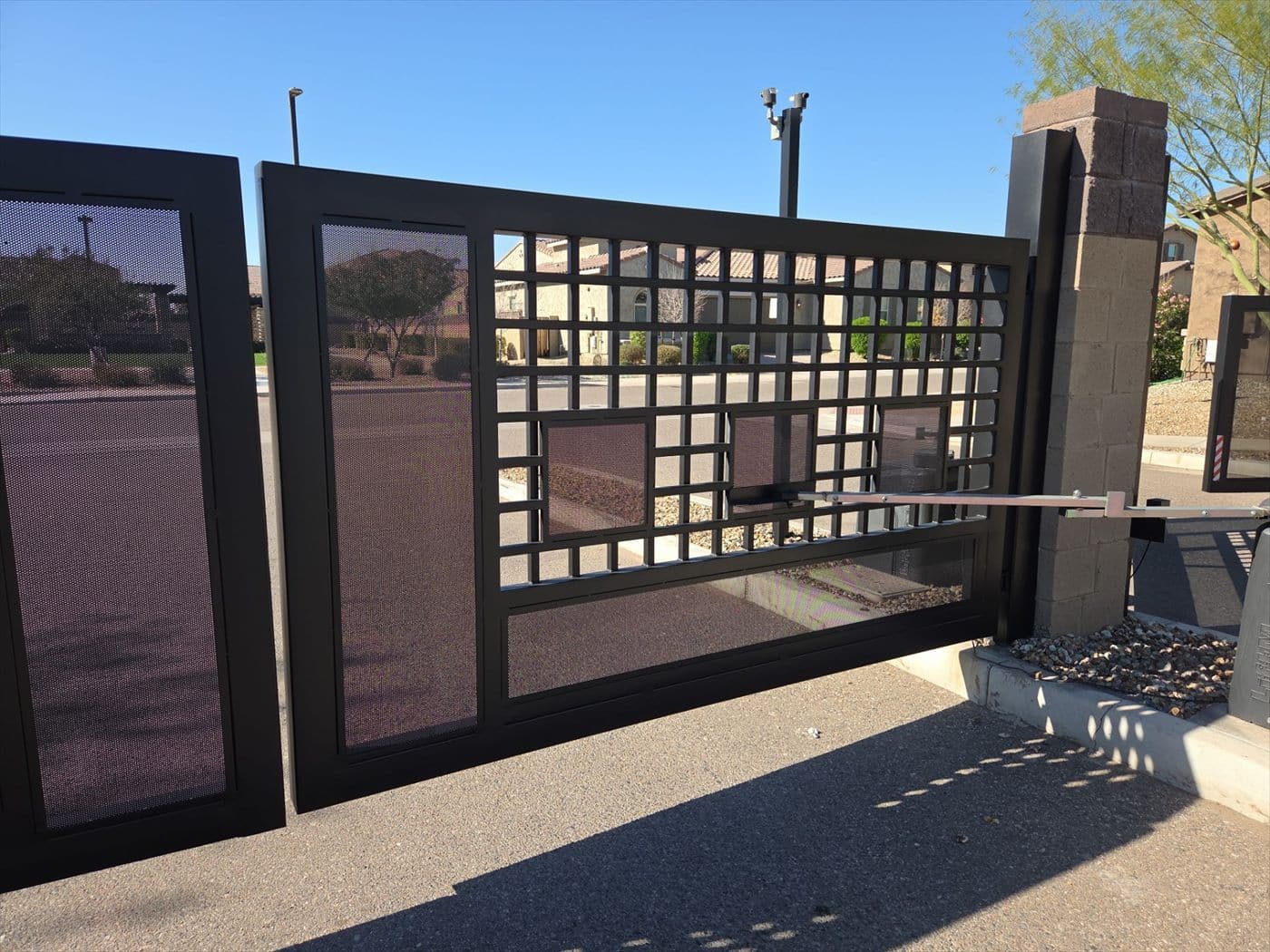 Decorative dark metal entry gate panels with masonry pillar.