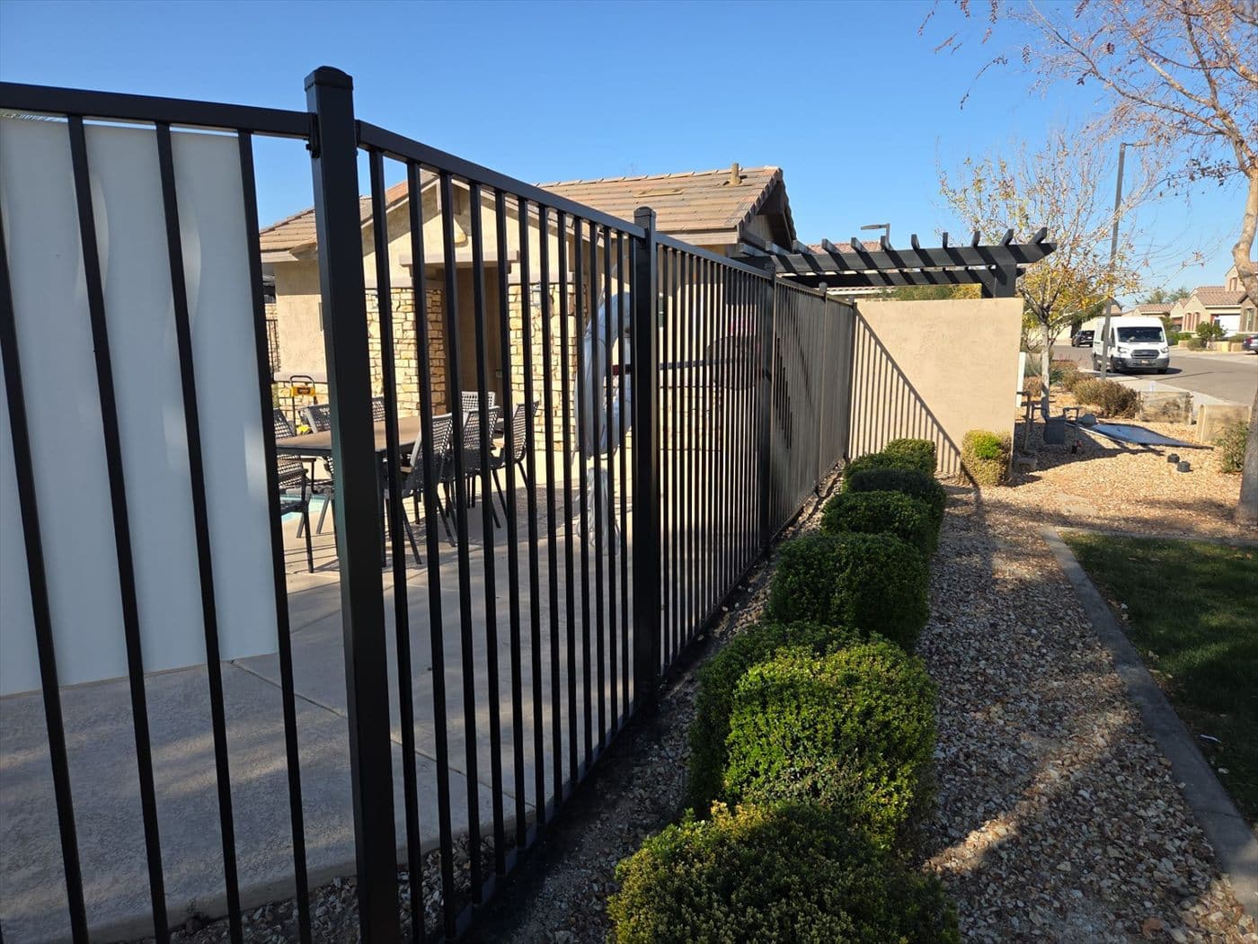 Black wrought iron fence along a landscaped community walkway.