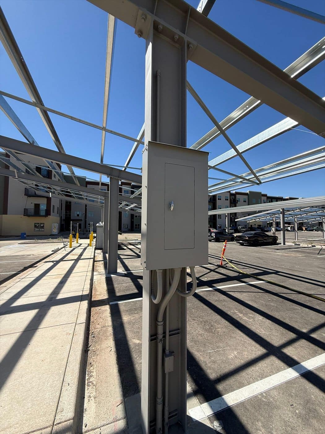 A finished gray-painted electrical panel on a carport column under the completed steel canopy.