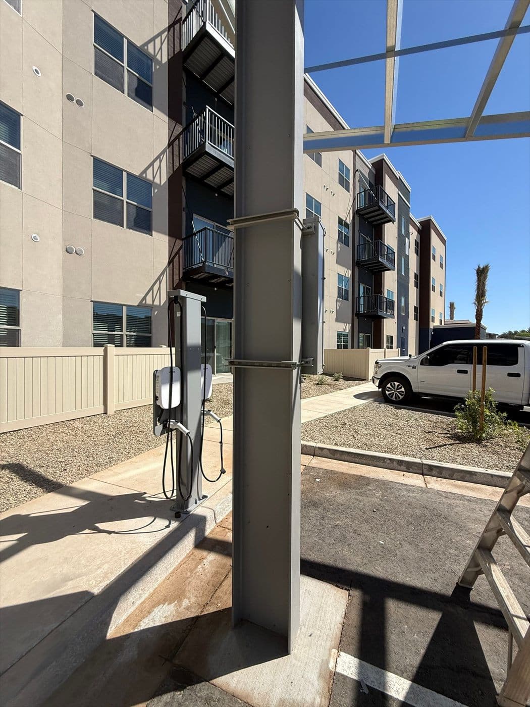 An EV charger and painted column beside an apartment building with the carport canopy above.