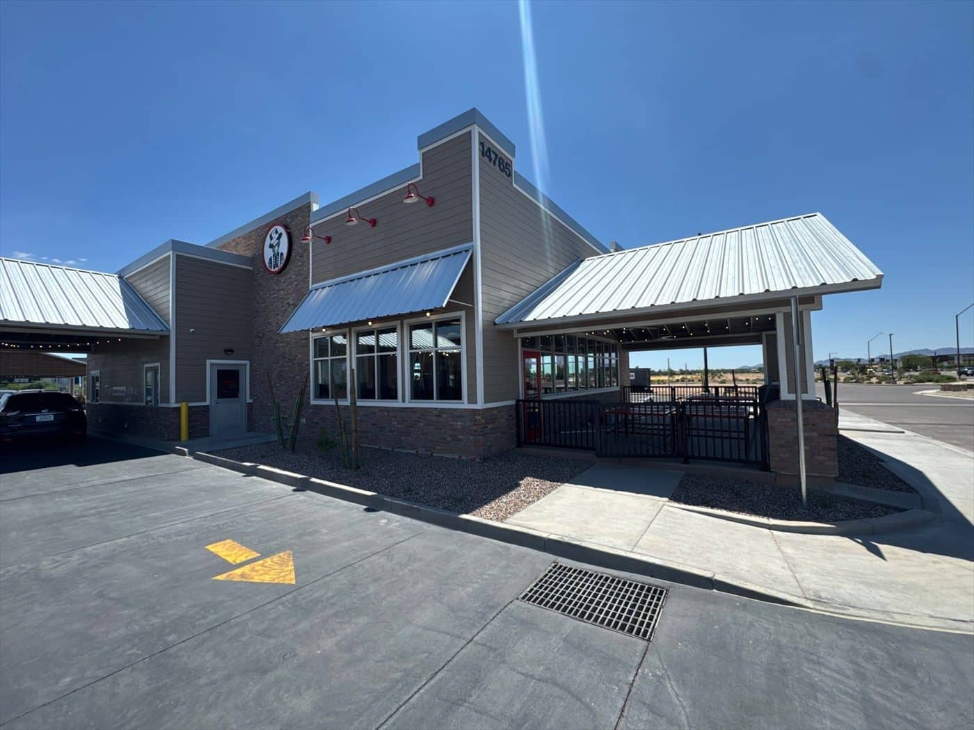 The finished restaurant exterior with metal roofs, Slim Chickens logo, and covered patio.
