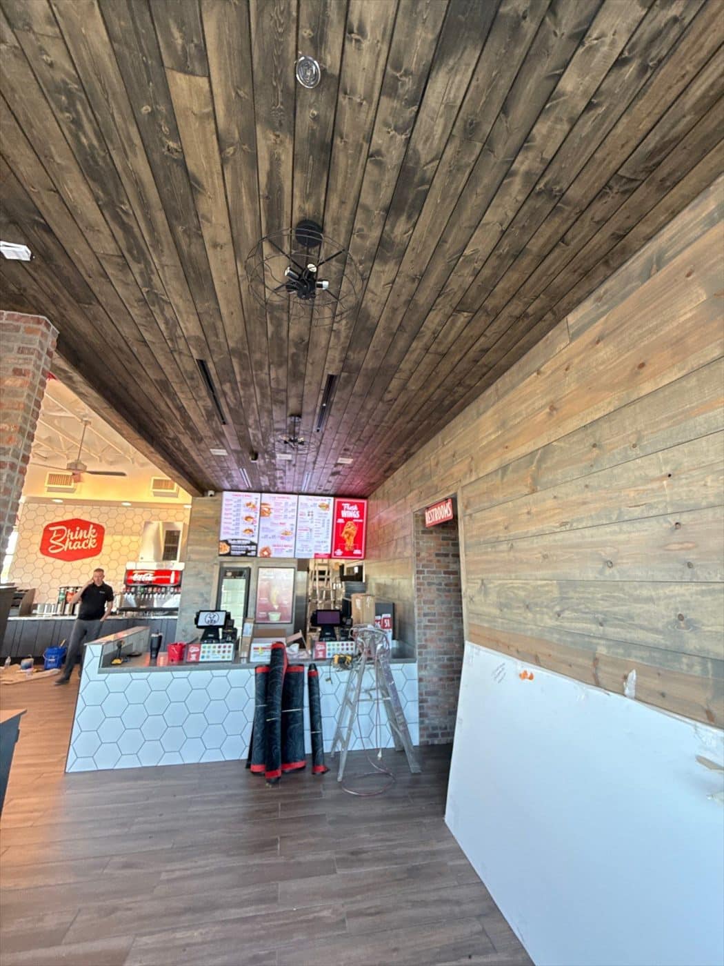 Finished interior dining and counter area with wood ceiling, wood floors, menu boards, and 'Drink Shack' station.