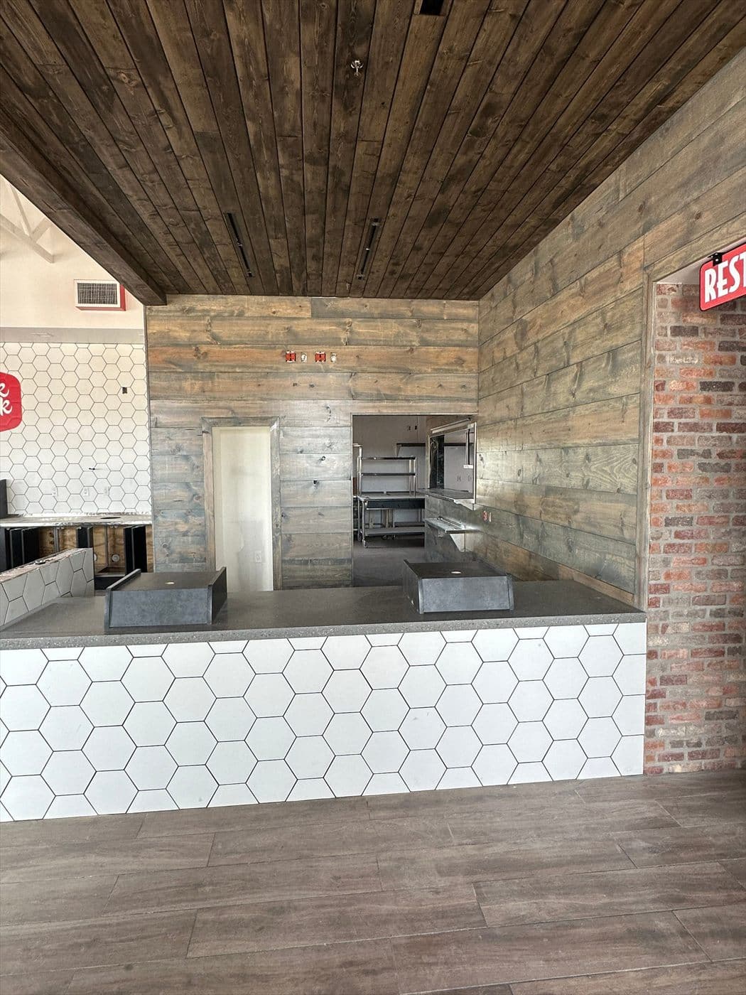 Finished interior showing a white honeycomb-tile service counter, wood plank walls, and stained wood ceiling.