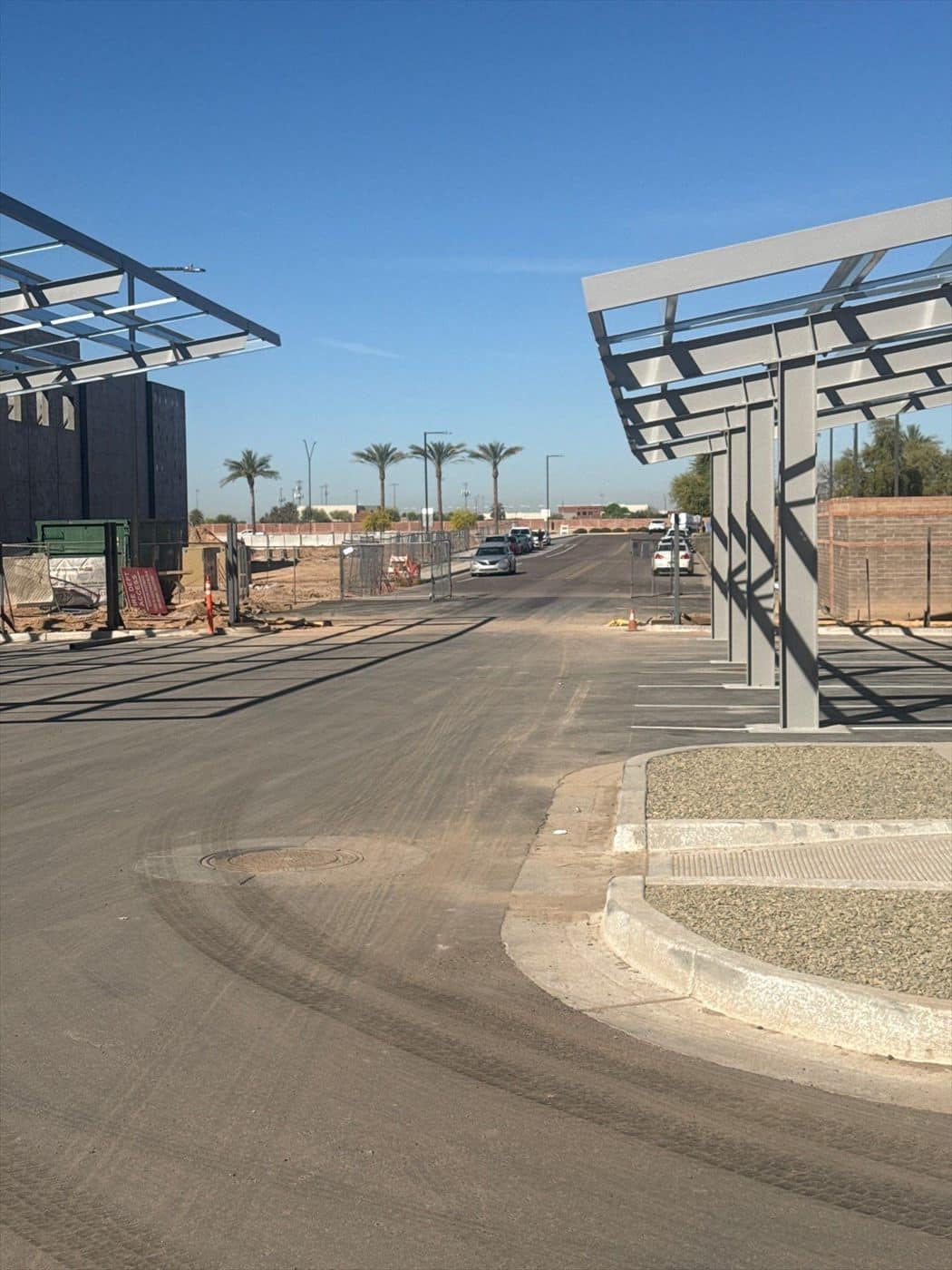 Unpainted steel solar carport canopy frames over a commercial parking lot before work begins.