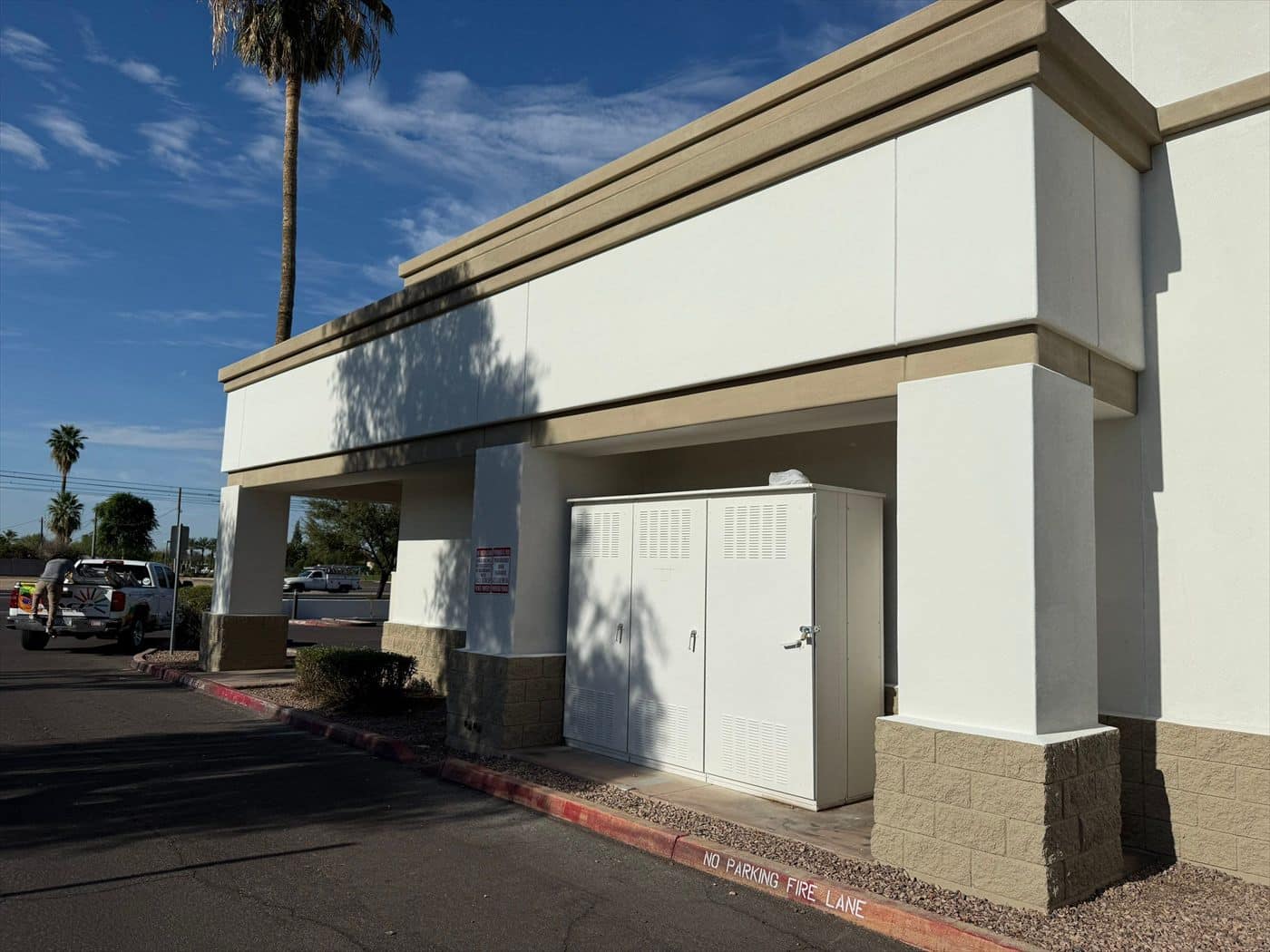 Completed building corner with covered entry, columns, and painted utility doors.