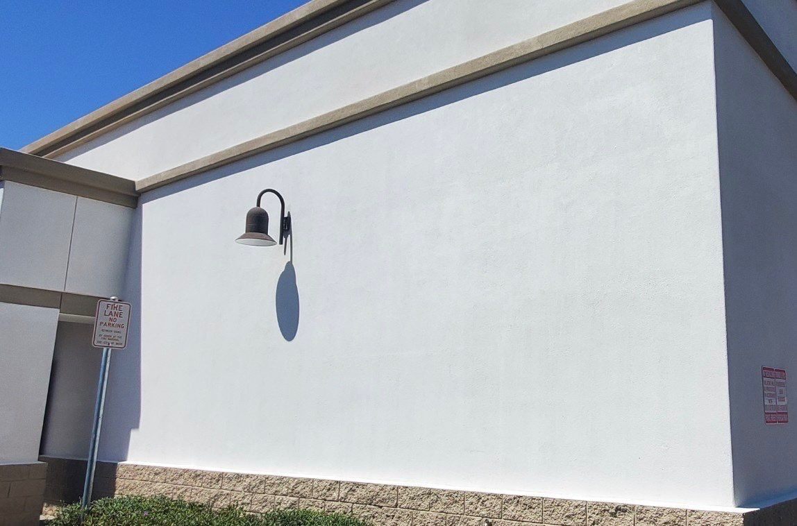Freshly painted white exterior wall with a wall-mounted sconce light.