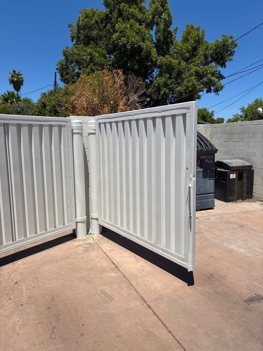 Freshly painted metal trash enclosure gate beside the dumpster area.