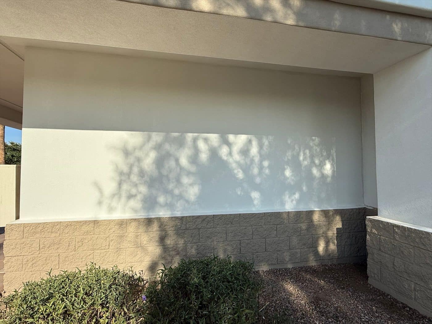 Repainted wall section under the overhang with block wainscot and landscaping.