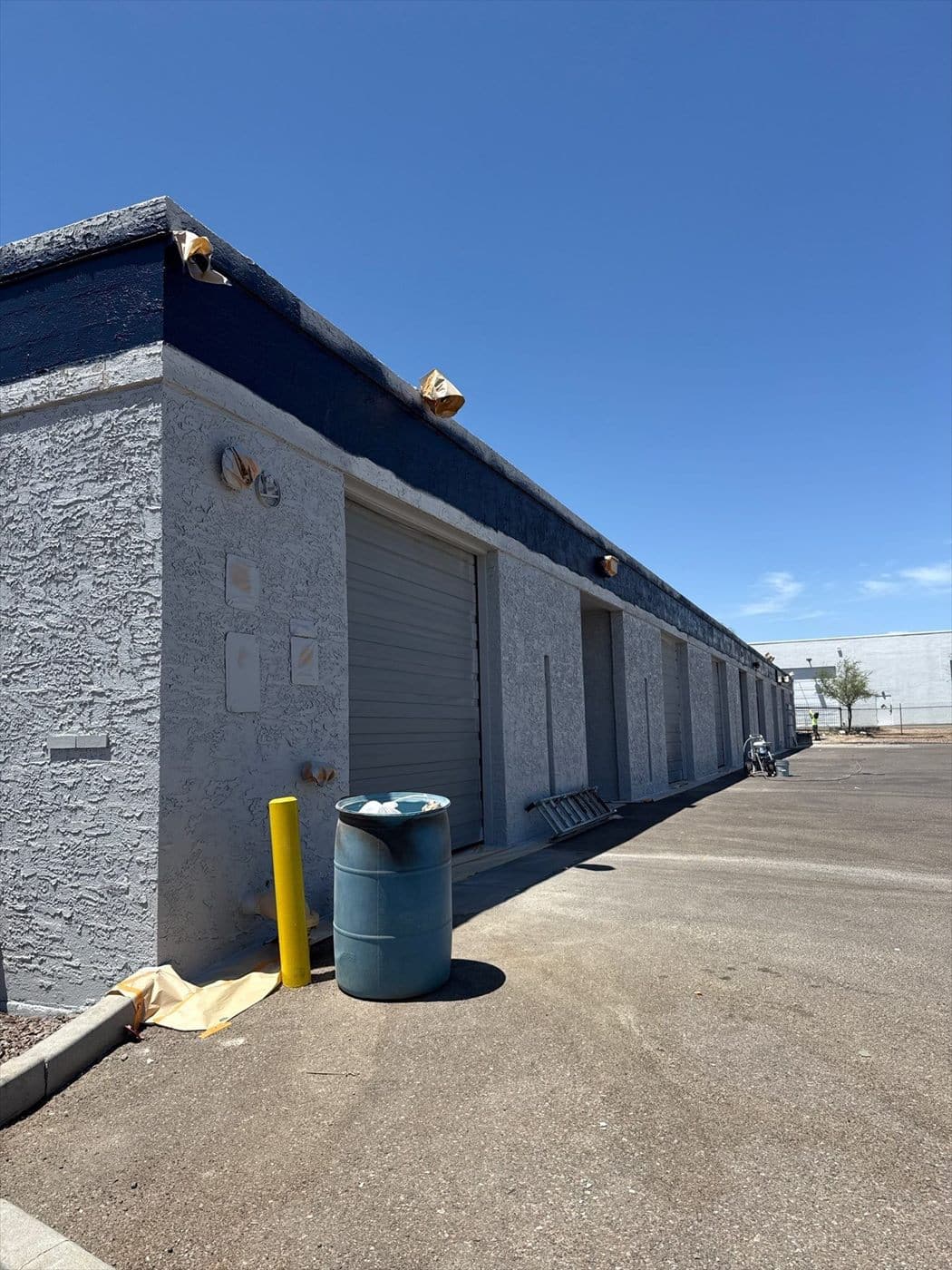 Row of loading bays with a roll-up door under the completed navy accent stripe.