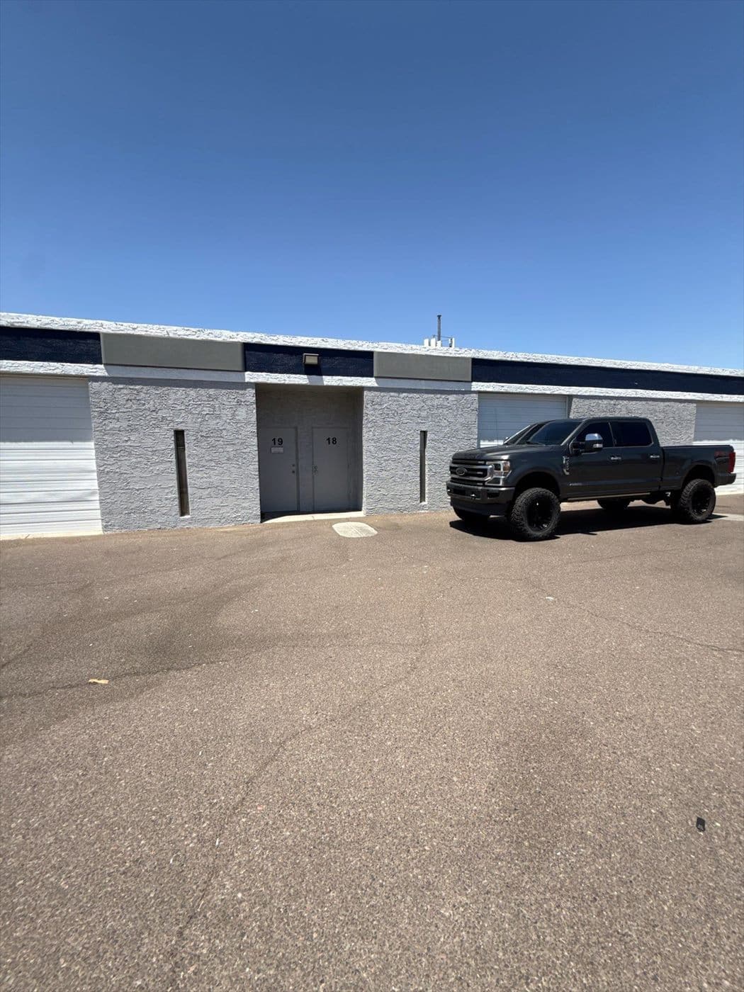Finished tenant units with a lifted pickup parked in front of the freshly painted gray facade.