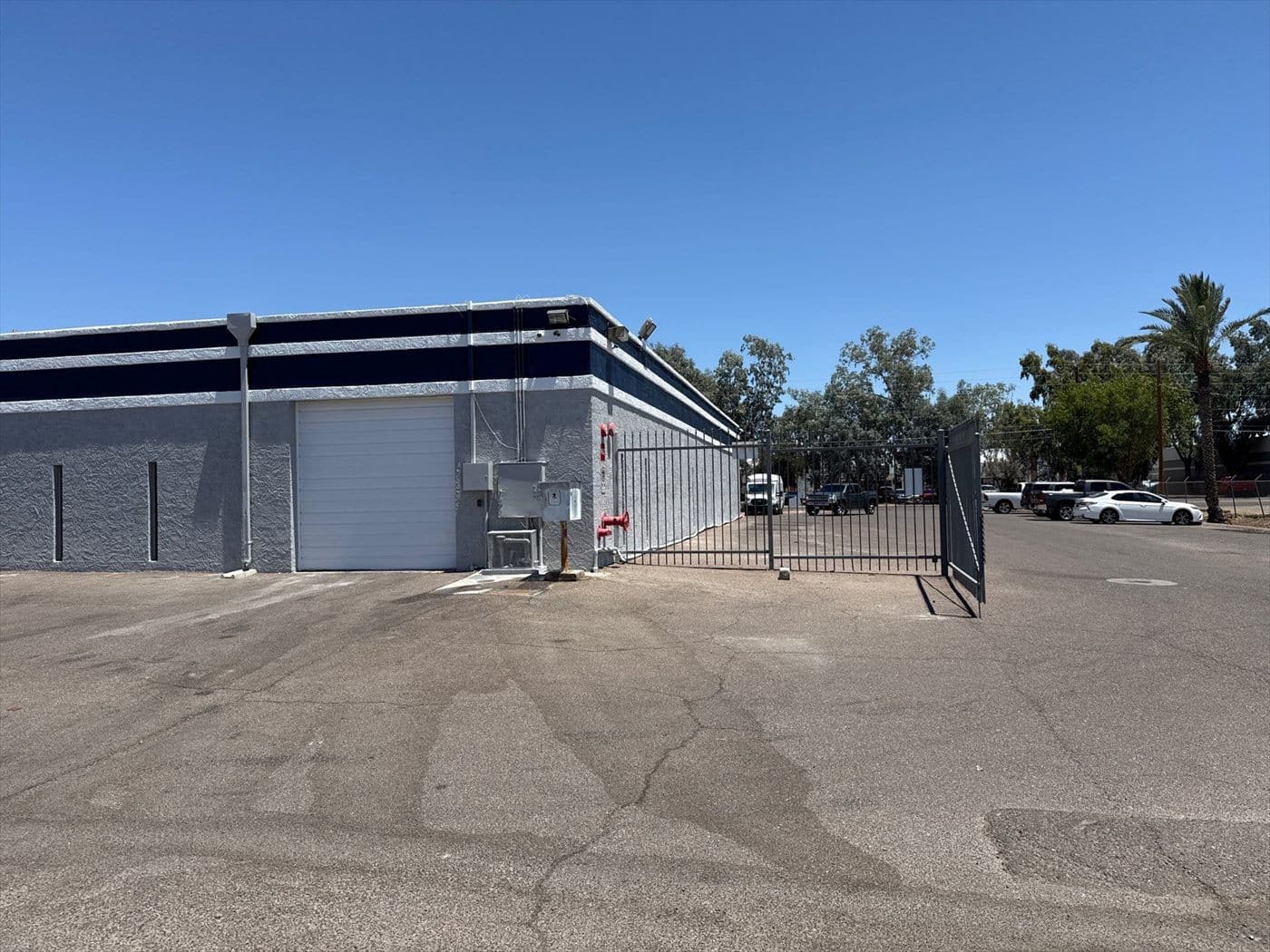 Repainted gray warehouse with new navy trim and a security gate at the roll-up door bay.