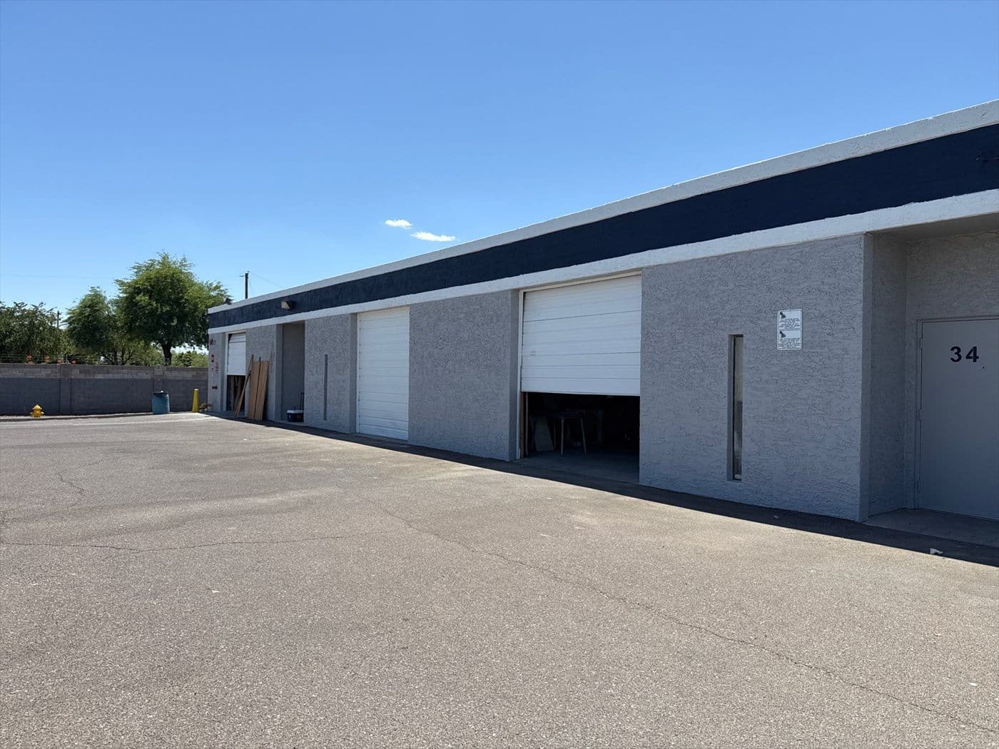 Repainted warehouse side with white roll-up doors and the finished navy band along the top.