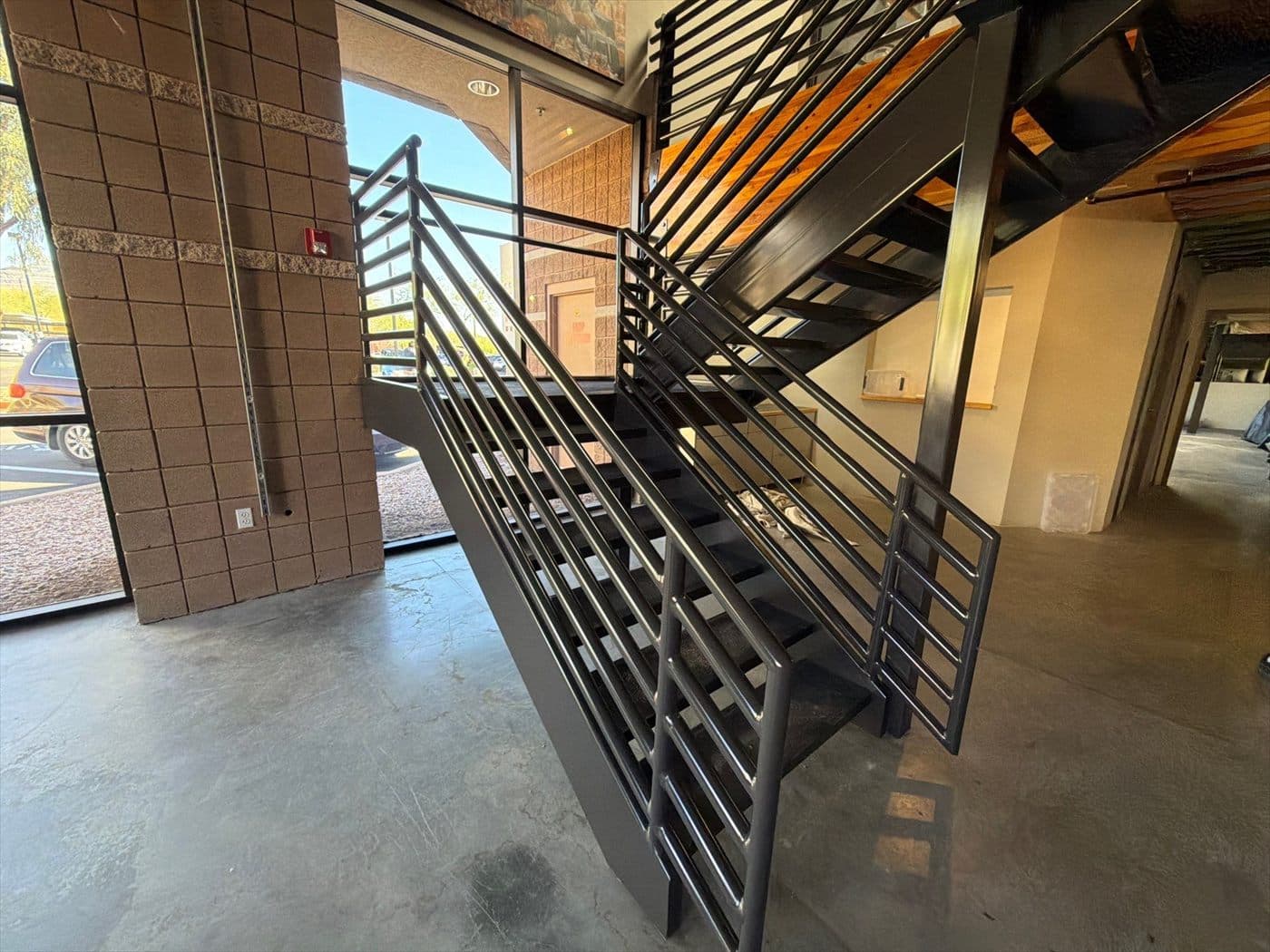 Completed black metal staircase and railings near the tiled entry column.