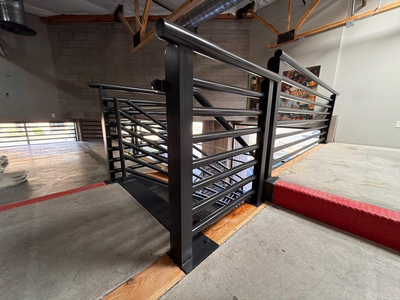 Completed black metal railing at a stair landing above the interior floor.