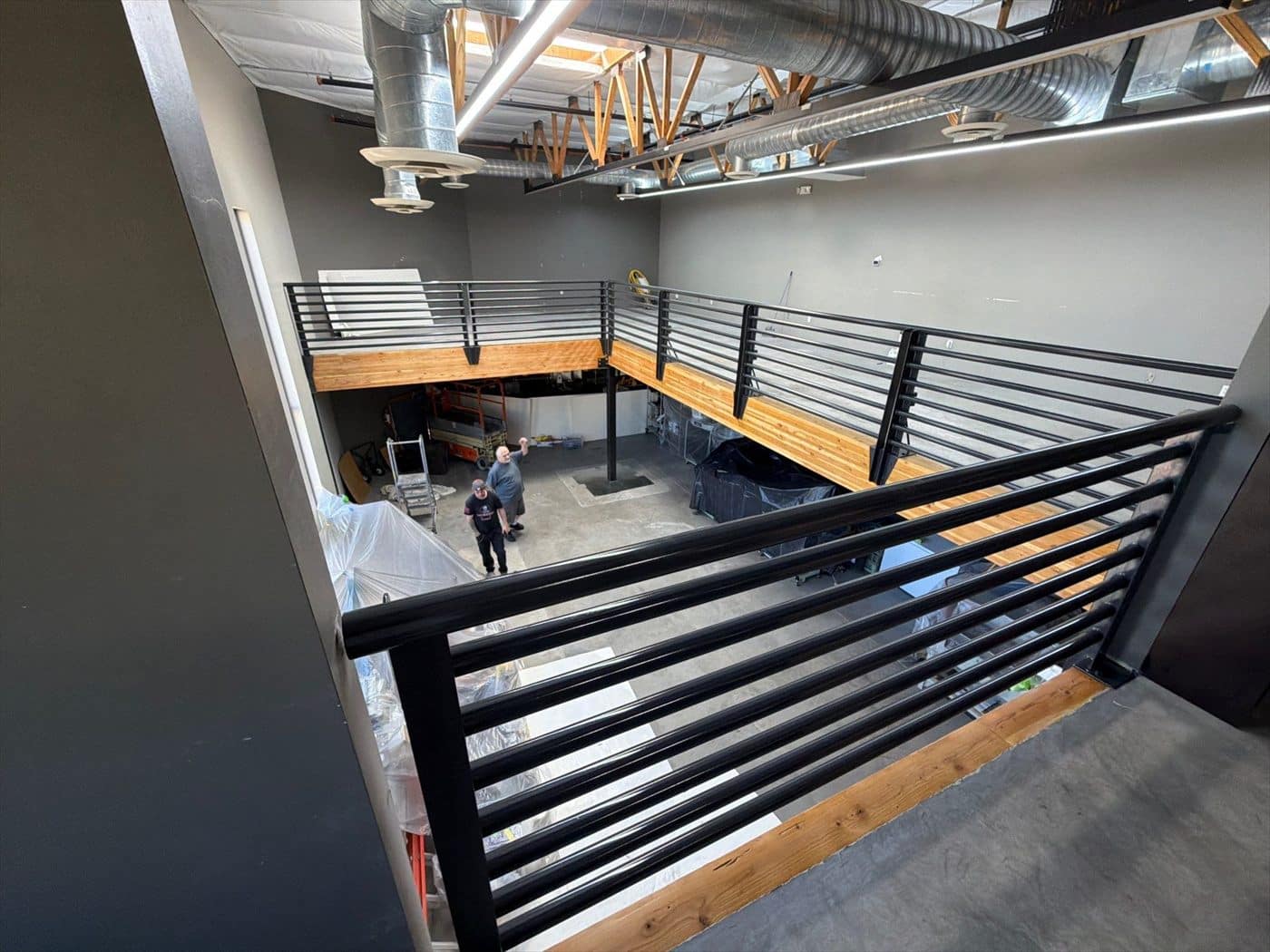 Overhead view of finished black mezzanine railings above the commercial interior.