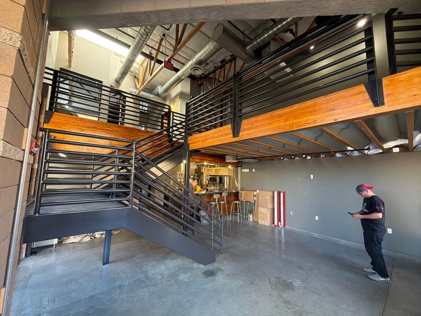Wide view of the finished black staircase and mezzanine railings in an open commercial interior.