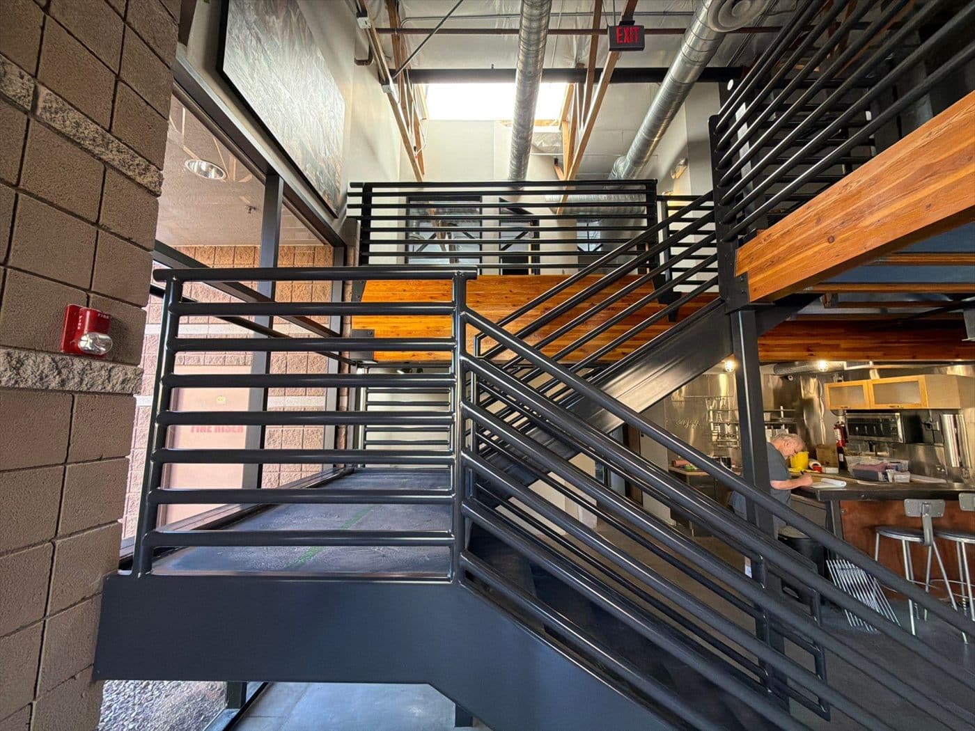 Finished black metal staircase and railings in a commercial space near the kitchen bar.