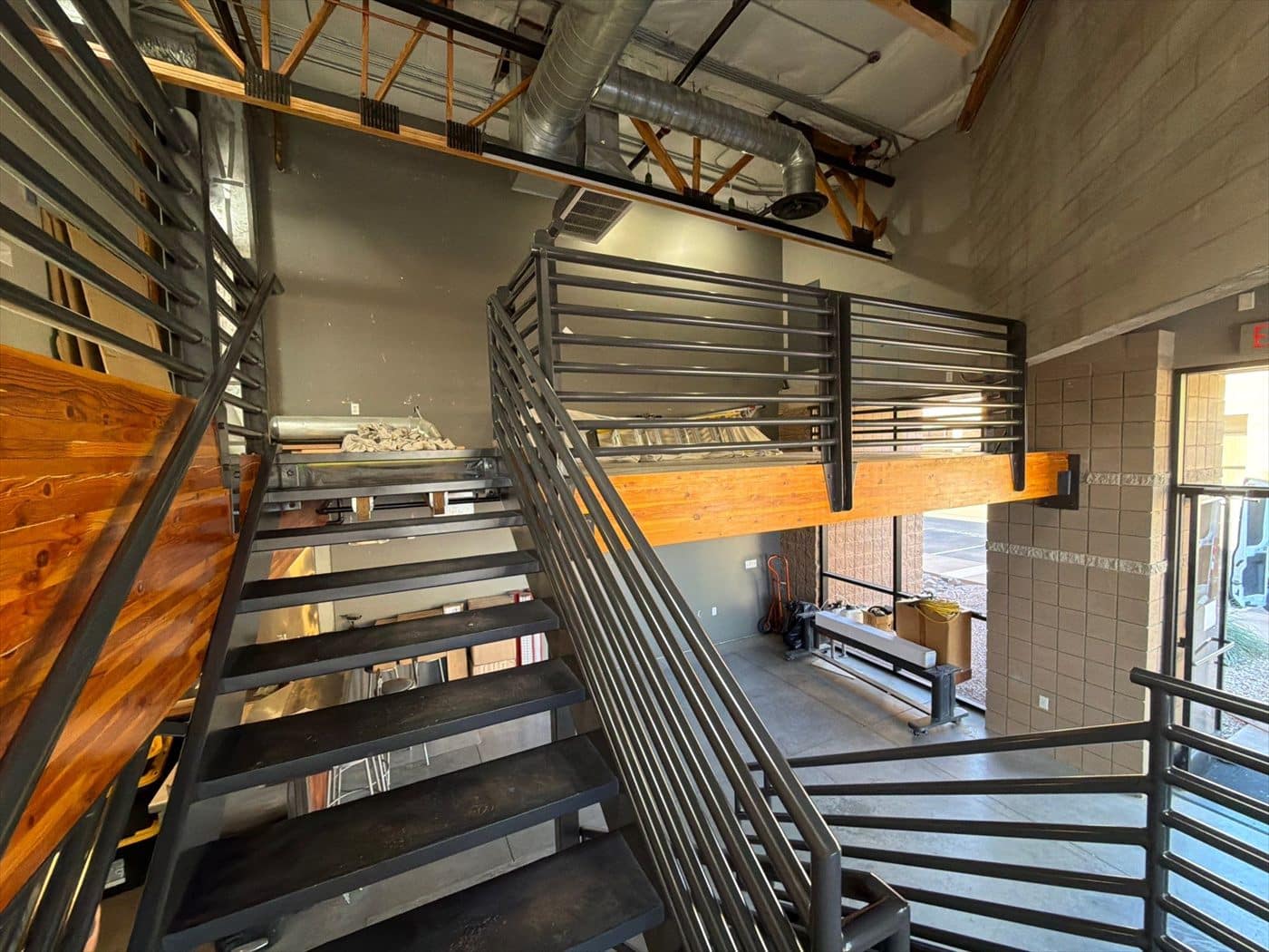 Finished black-coated stairwell railings with wood accent panels in the commercial interior.