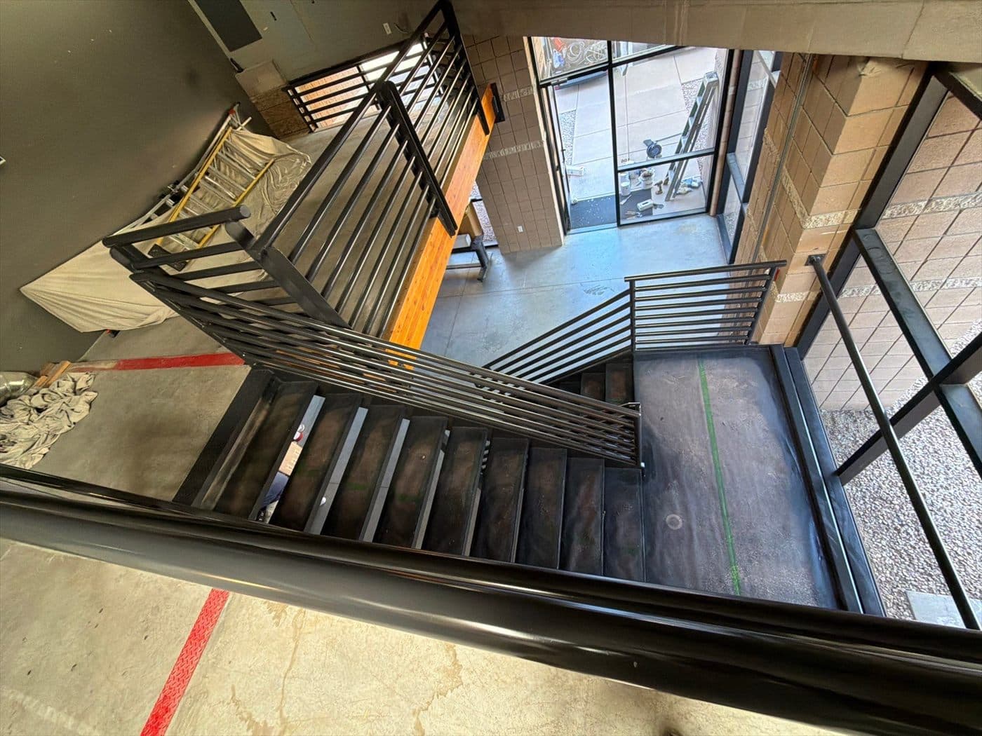 Looking down the stairwell at finished black metal railings near the entrance.