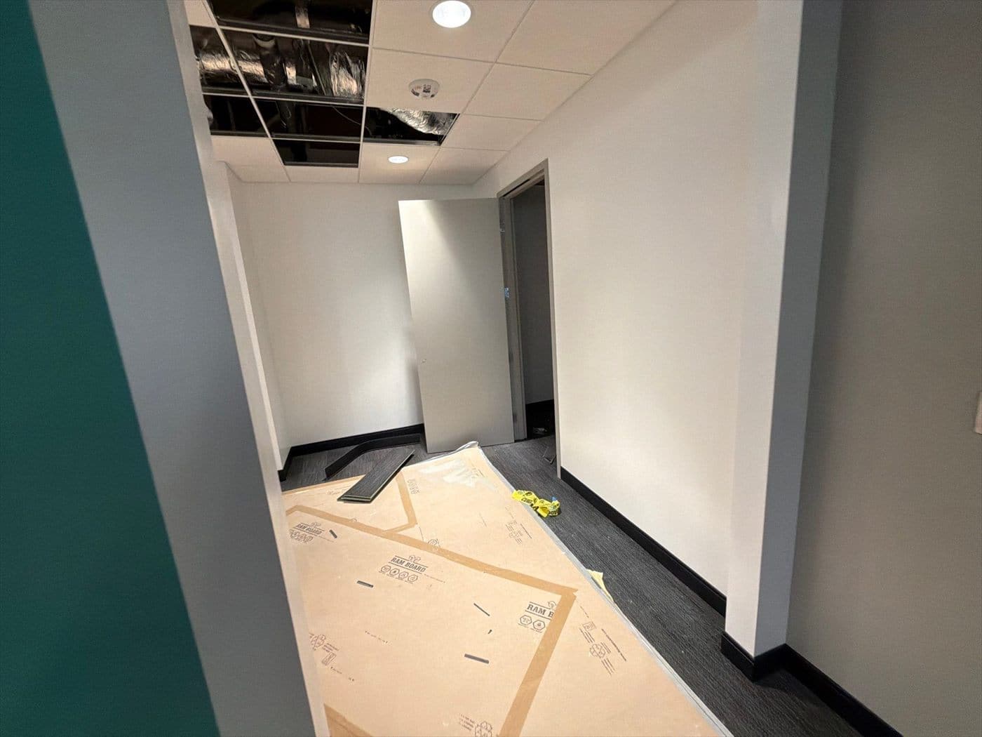 Finished hallway with white walls, floor protection, and a teal accent edge.